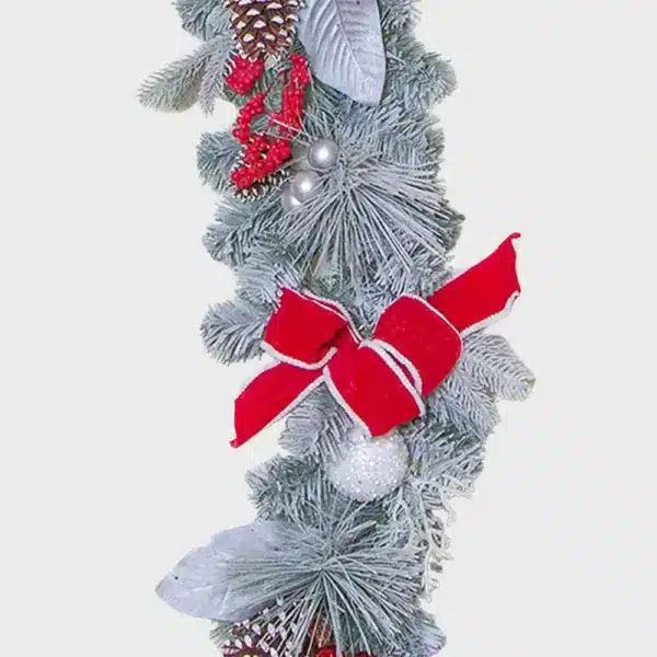 Decorative white frosted Christmas garland with red ribbons and baubles close up view
