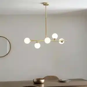 Modern satin brass linear bar pendant light with glass shades above dining table