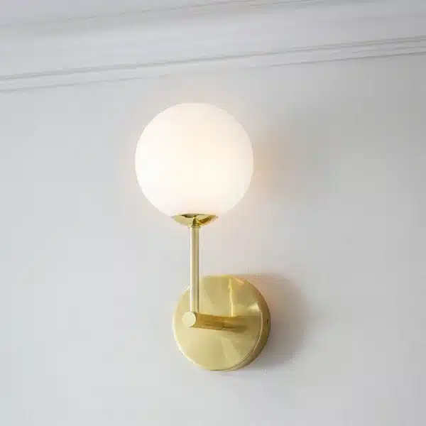 Wall light installed on wall brushed brass finish with opal glass globe